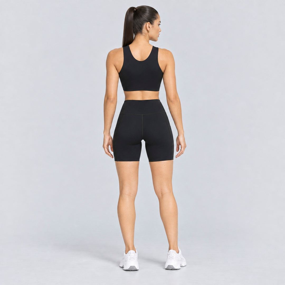 Conjunto deportivo negro visto desde atrás: top sin mangas y short biker tiro alto.