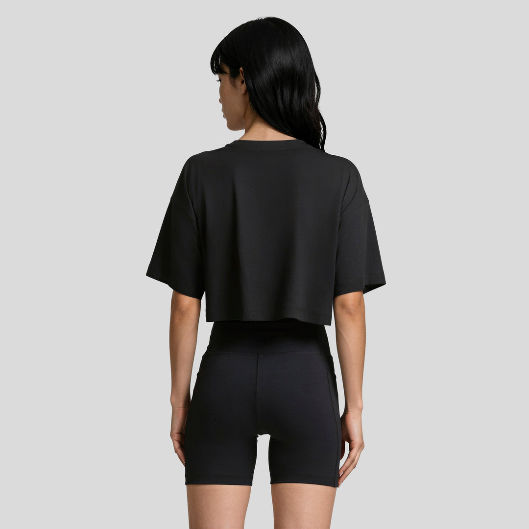 Conjunto mujer negro con playera corta holgada y short ajustado, vista posterior