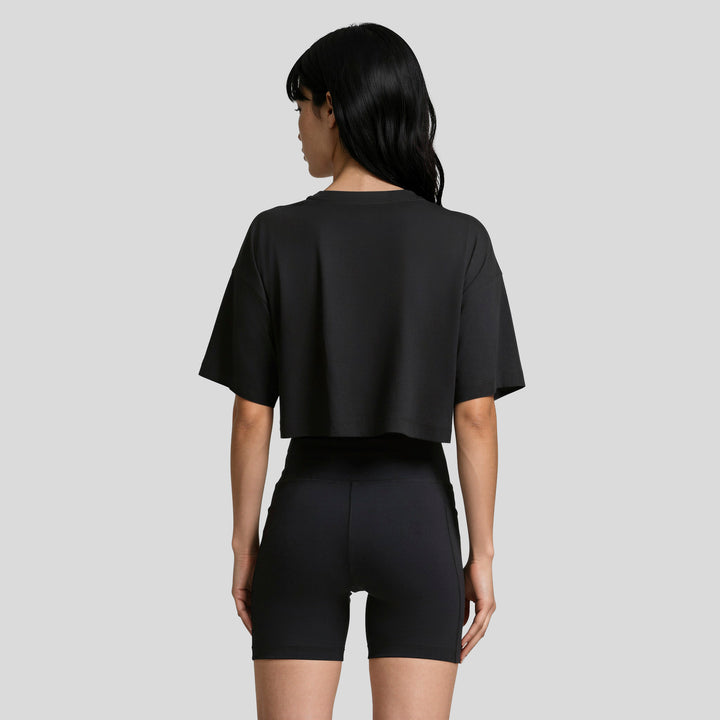 Conjunto mujer negro con playera corta holgada y short ajustado, vista posterior