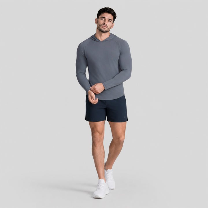 Conjunto deportivo: playera gris de manga larga con capucha y short azul marino.